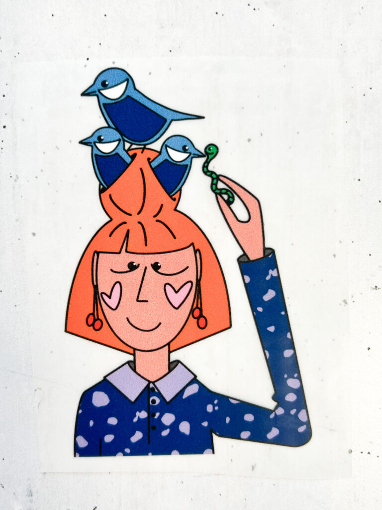 Illustration von Anke: Eine Frau mit orangefarbenem Haar, auf dem drei blaue Vögel sitzen, hält einen grünen Wurm in der Hand. Stilvoll und farbenfroh.