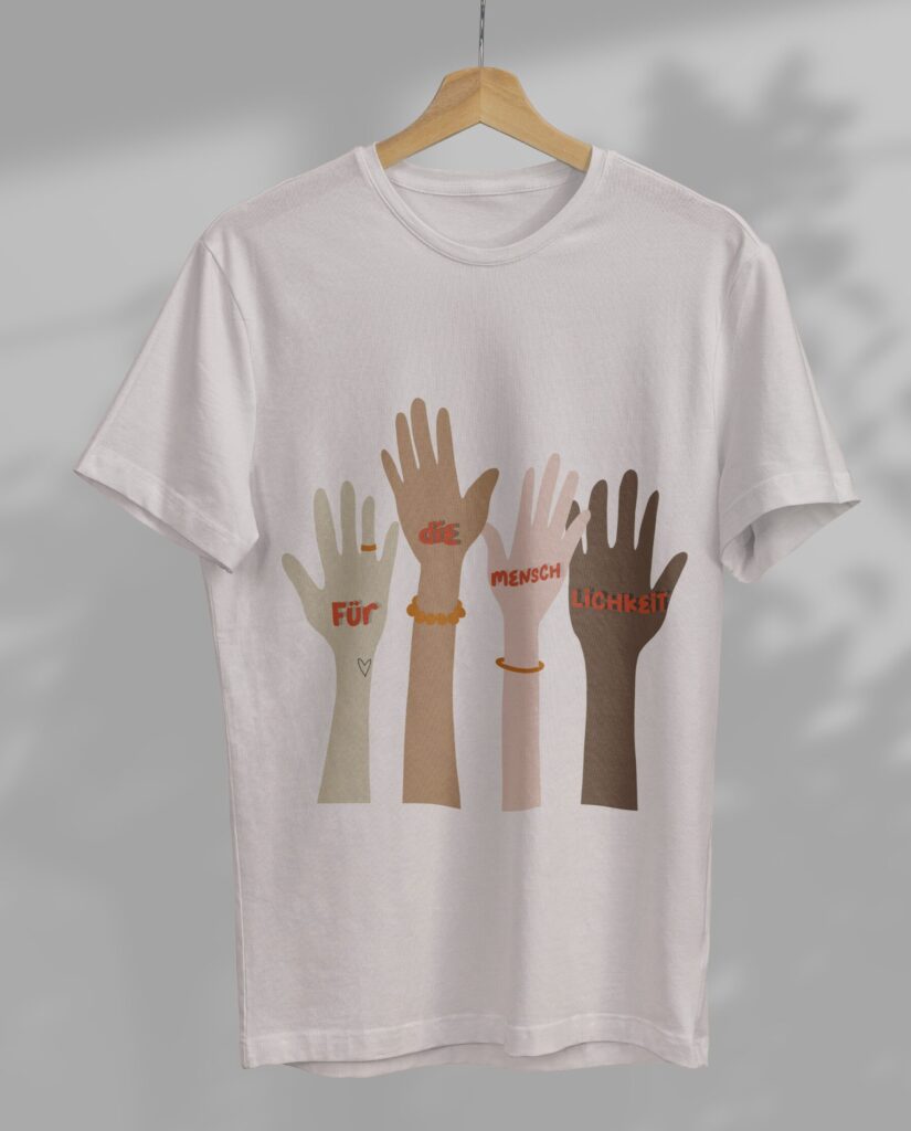 Weißes T-Shirt mit dem Bügelbild Menschlichkeit XXL, das vier Hände in verschiedenen Hauttönen mit dem Schriftzug Für die Menschlichkeit zeigt.