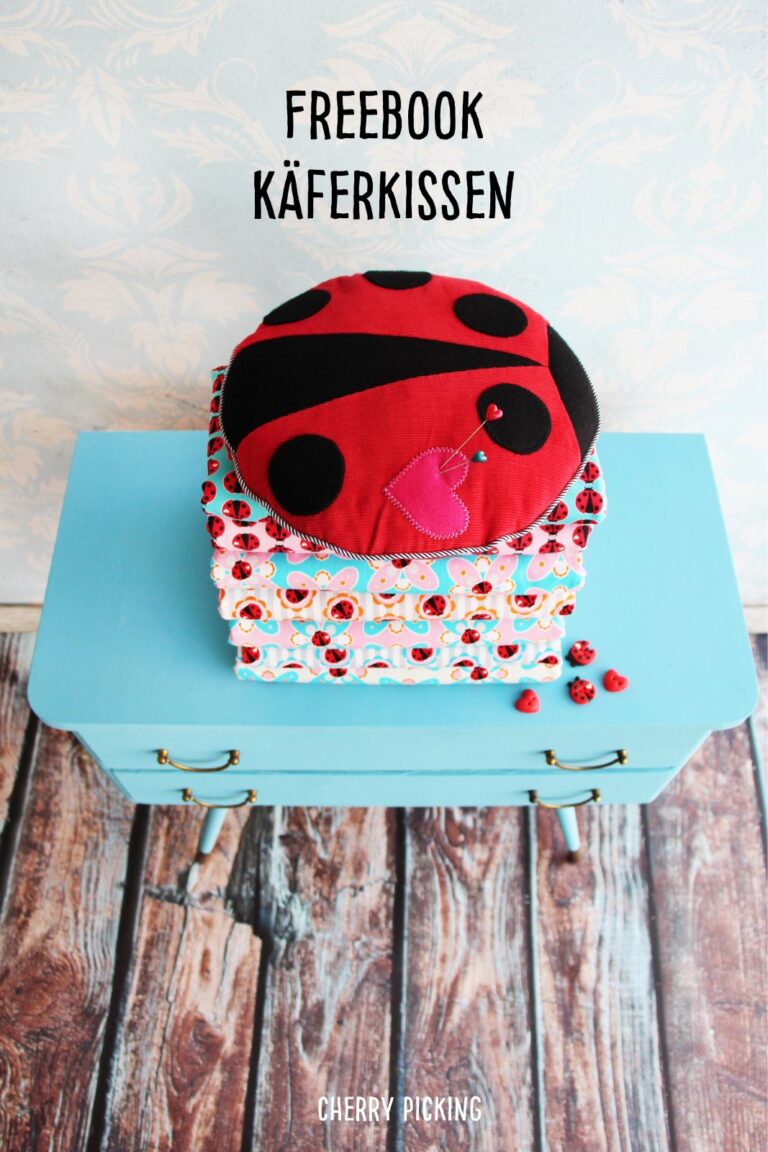 Rundes Marienkäfer-Kissen in Rot und Schwarz mit rosa Herz auf einem türkisen Schränkchen